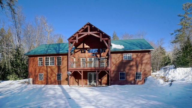 snow covered back of property featuring a deck