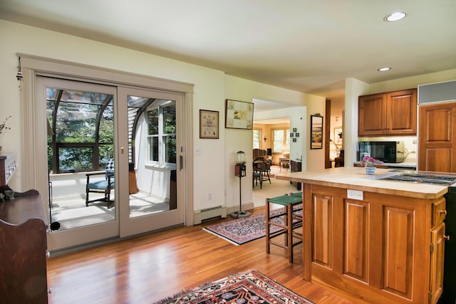 kitchen featuring a baseboard heating unit, a breakfast bar area, and light hardwood / wood-style flooring