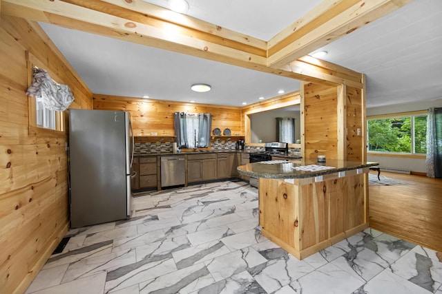 kitchen with wooden walls, kitchen peninsula, and appliances with stainless steel finishes