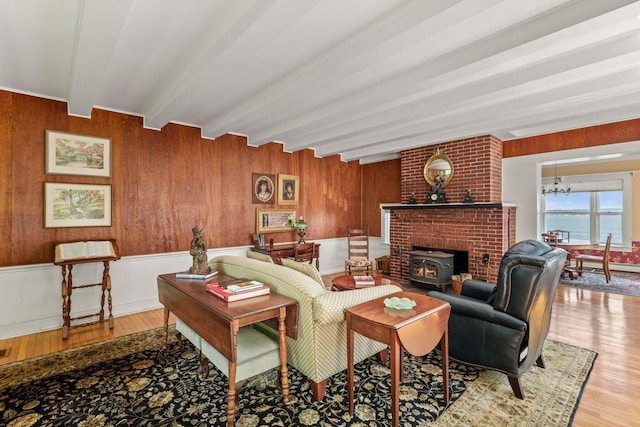 LTS23A Birch Is, South Bristol, ME 04568 - living room with beamed ceiling, wood finished floors, a chandelier, a wood stove, and wooden walls