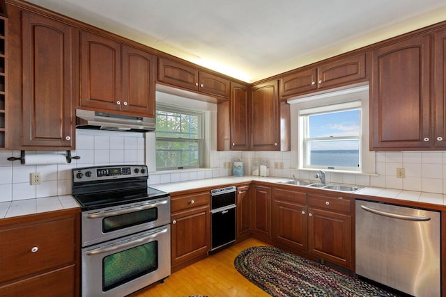 LTS23A Birch Is, South Bristol, ME 04568 - kitchen featuring appliances with stainless steel finishes, tile counters, under cabinet range hood, and backsplash