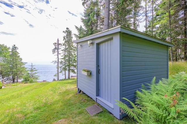 view of outdoor structure featuring a water view and a yard