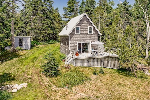 rear view of house featuring a wooden deck, a yard, and a storage unit