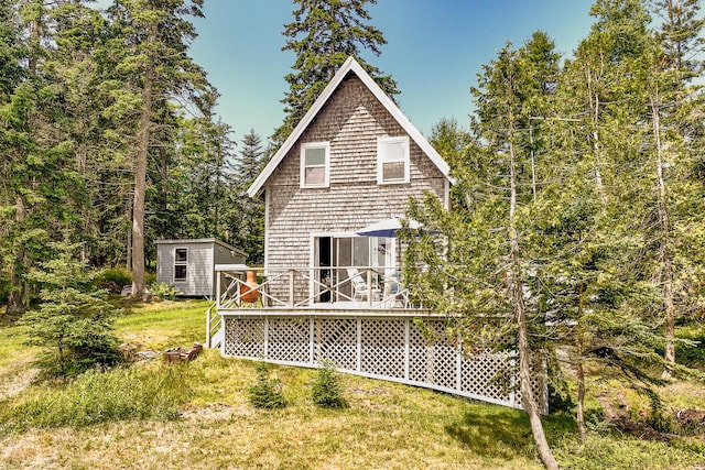 back of house featuring a deck, a shed, and a lawn