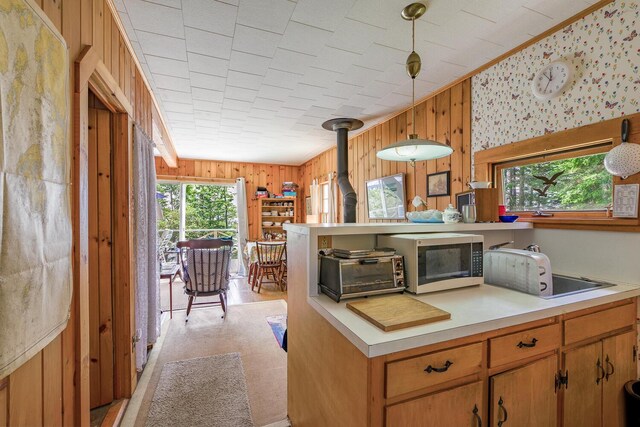 kitchen featuring a wood stove, wood walls, and decorative light fixtures