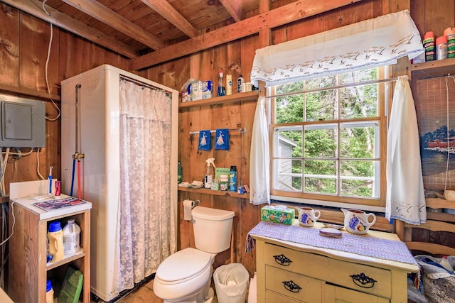 bathroom with toilet, electric panel, and wood walls