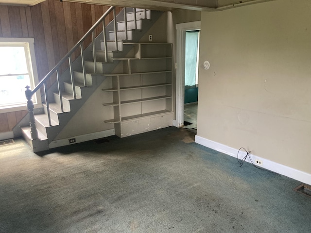 basement with dark carpet and wood walls