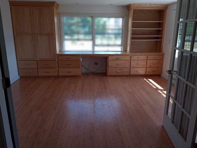 interior space with wood-type flooring, built in desk, and a healthy amount of sunlight