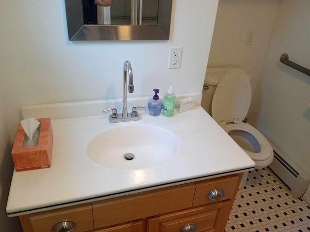 bathroom with toilet, vanity, a baseboard heating unit, and tile patterned floors