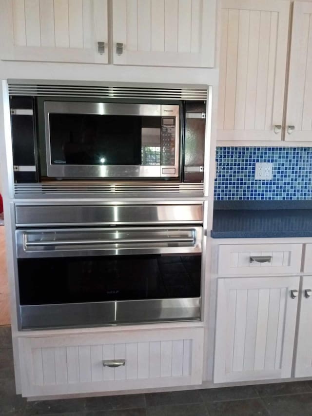 kitchen with dark tile patterned flooring, white cabinetry, and appliances with stainless steel finishes