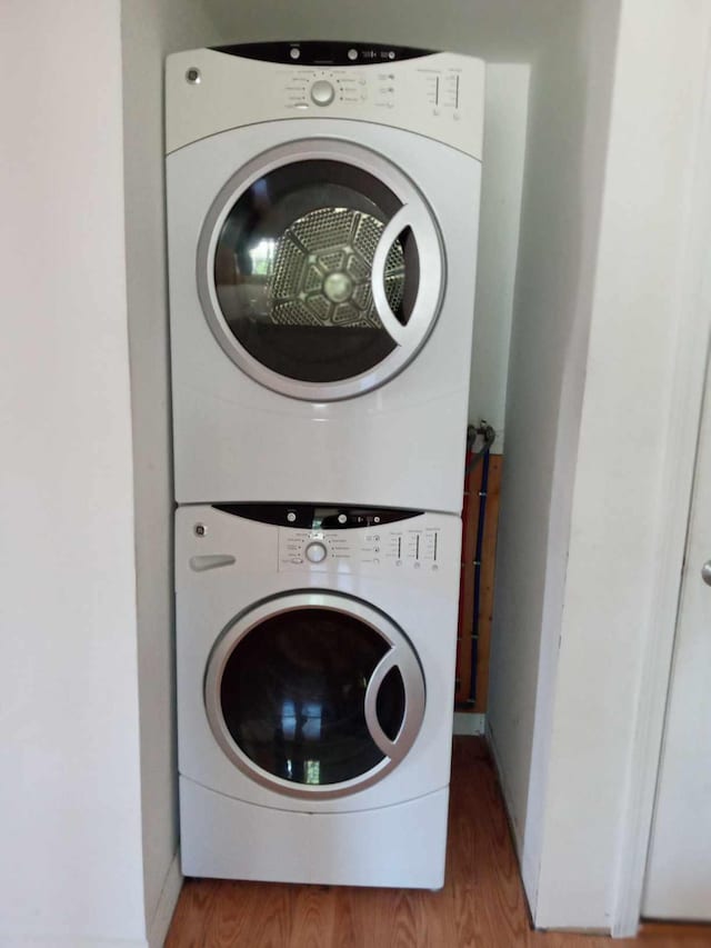 laundry area featuring stacked washer / dryer and hardwood / wood-style flooring