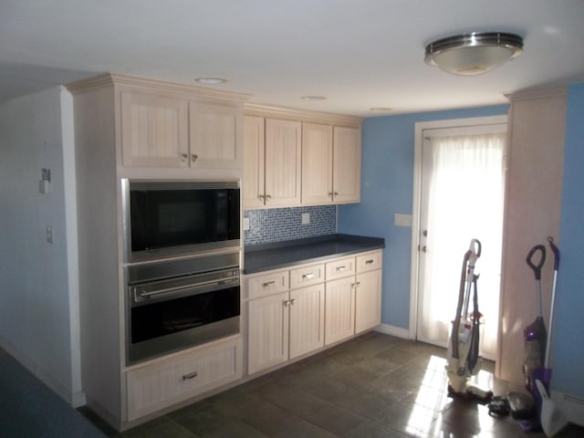 kitchen featuring black microwave, decorative backsplash, and stainless steel oven