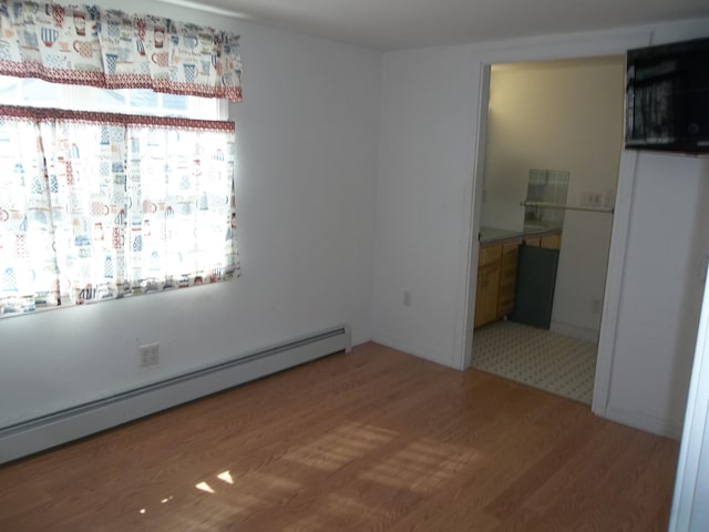 empty room featuring a baseboard heating unit and wood-type flooring