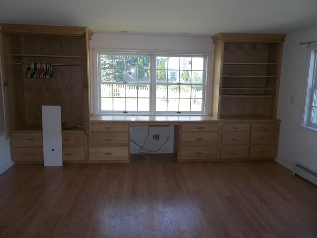 unfurnished bedroom featuring a baseboard radiator, dark hardwood / wood-style flooring, and built in desk