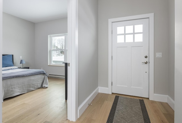 foyer entrance featuring a baseboard heating unit and light hardwood / wood-style floors