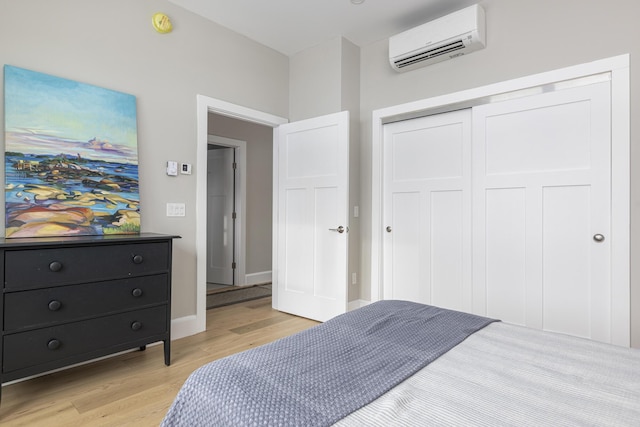 bedroom with a wall mounted air conditioner, light wood-type flooring, and a closet