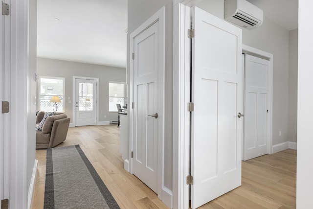 hallway with a wall unit AC and light hardwood / wood-style floors