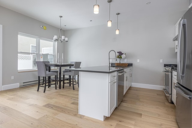 kitchen with decorative light fixtures, sink, white cabinets, stainless steel appliances, and light hardwood / wood-style flooring