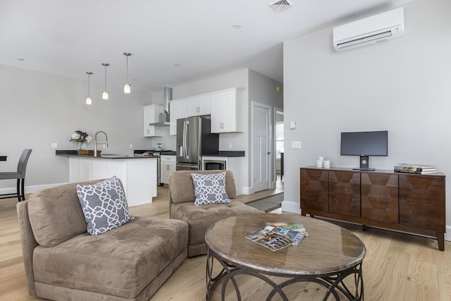 living room featuring sink, a wall mounted AC, and light hardwood / wood-style floors