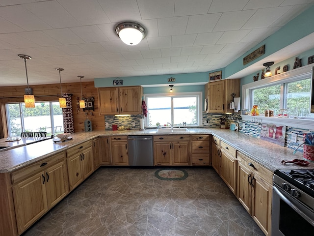 kitchen featuring pendant lighting, sink, stainless steel appliances, decorative backsplash, and kitchen peninsula