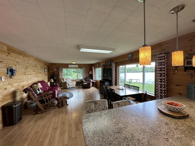 dining space featuring light wood-type flooring and wood walls