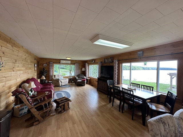 living room featuring light hardwood / wood-style flooring, wood walls, and a water view