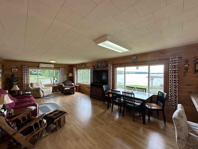 dining space with wood-type flooring, an AC wall unit, and wood walls