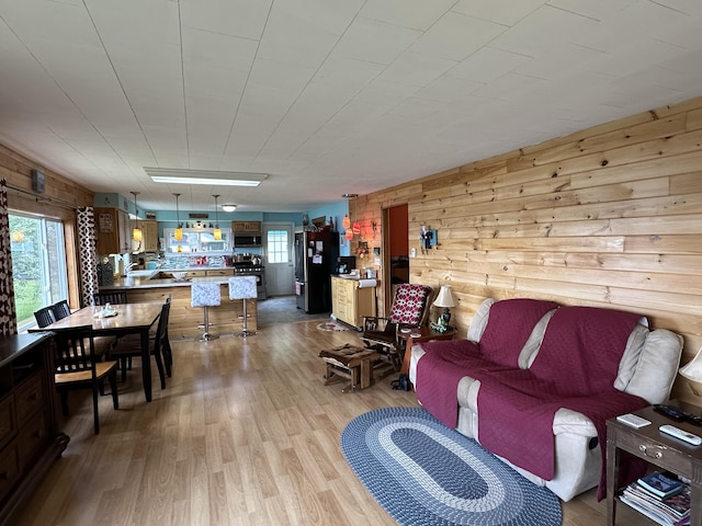 living room featuring plenty of natural light, light hardwood / wood-style floors, and wooden walls