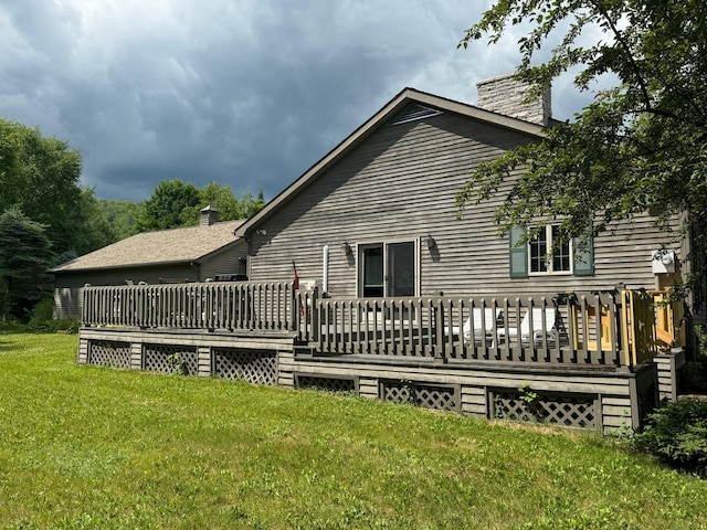 rear view of property featuring a deck and a lawn