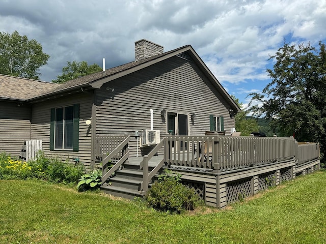 rear view of property featuring a deck, ac unit, and a lawn