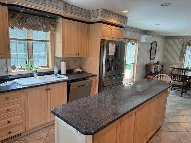 kitchen with light brown cabinetry, sink, light tile patterned floors, an AC wall unit, and stainless steel appliances