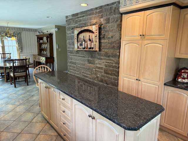 kitchen with decorative light fixtures, a center island, dark stone counters, and light brown cabinetry