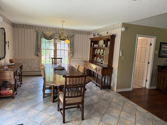 dining space featuring hardwood / wood-style flooring, a baseboard heating unit, and an inviting chandelier