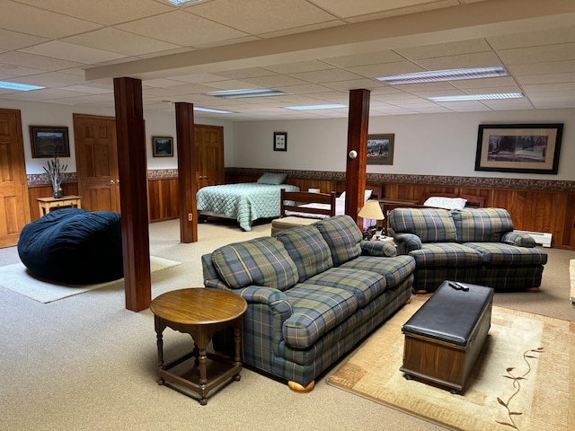 living room with a paneled ceiling, carpet flooring, and wooden walls