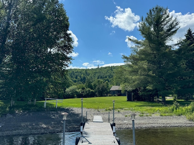 view of dock featuring a lawn and a water view