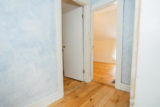 hallway with light wood-type flooring and lofted ceiling