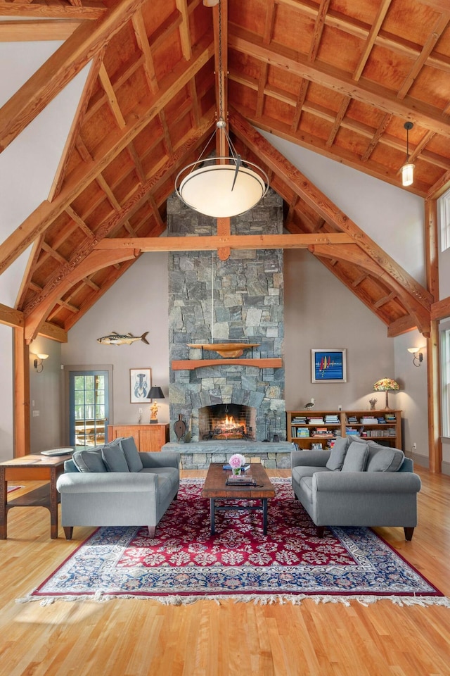 living room featuring wood ceiling, hardwood / wood-style floors, a fireplace, high vaulted ceiling, and beam ceiling