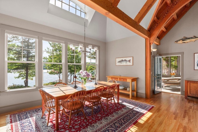 dining space with high vaulted ceiling, wood-type flooring, plenty of natural light, and an inviting chandelier