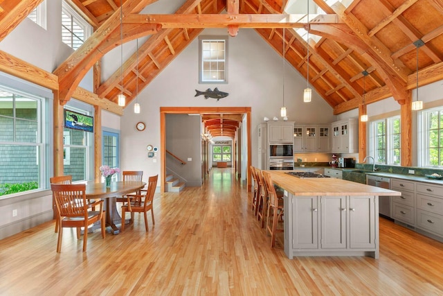 kitchen featuring gray cabinets, a kitchen island, pendant lighting, and high vaulted ceiling