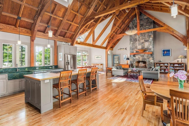 kitchen featuring pendant lighting, a kitchen island, a stone fireplace, gray cabinets, and high vaulted ceiling