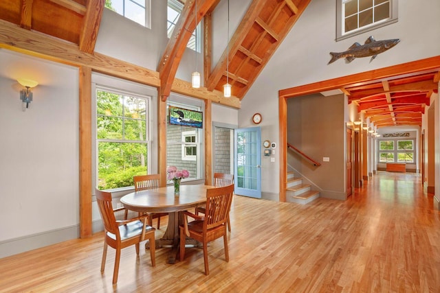 dining room with high vaulted ceiling, light hardwood / wood-style flooring, and beamed ceiling