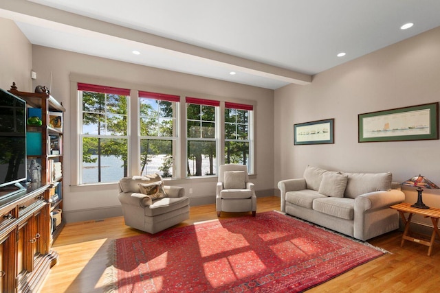 living room featuring a water view, plenty of natural light, beamed ceiling, and hardwood / wood-style flooring