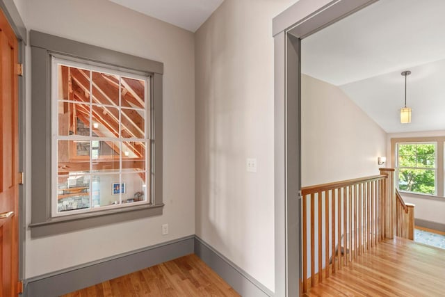 hall with vaulted ceiling and light hardwood / wood-style flooring