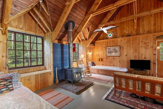 bedroom with wood ceiling, beamed ceiling, a wood stove, wood walls, and high vaulted ceiling