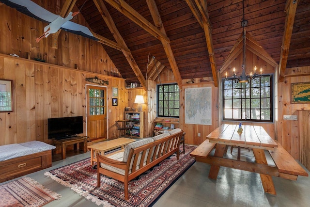 living room with lofted ceiling with beams, wood walls, an inviting chandelier, and wooden ceiling