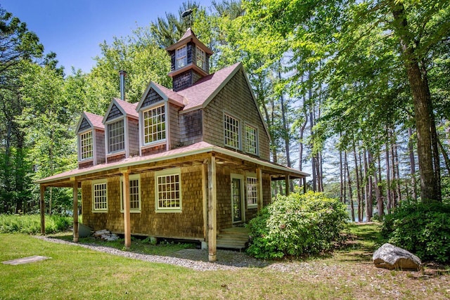 view of side of property with covered porch and a yard