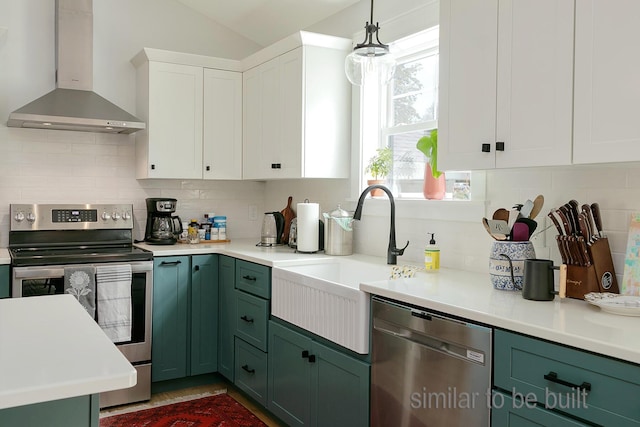 kitchen featuring white cabinetry, appliances with stainless steel finishes, backsplash, decorative light fixtures, and wall chimney exhaust hood