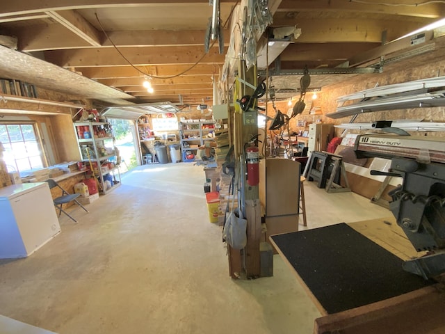 basement featuring refrigerator and a workshop area