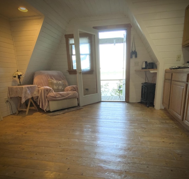 additional living space with light hardwood / wood-style floors, wood walls, and vaulted ceiling