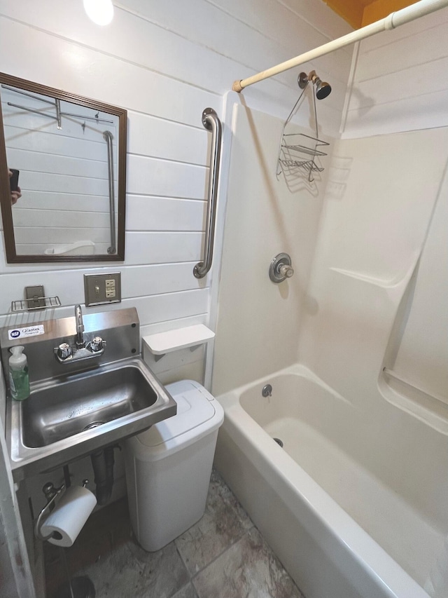 full bathroom with toilet, shower / bath combination, sink, and wooden walls